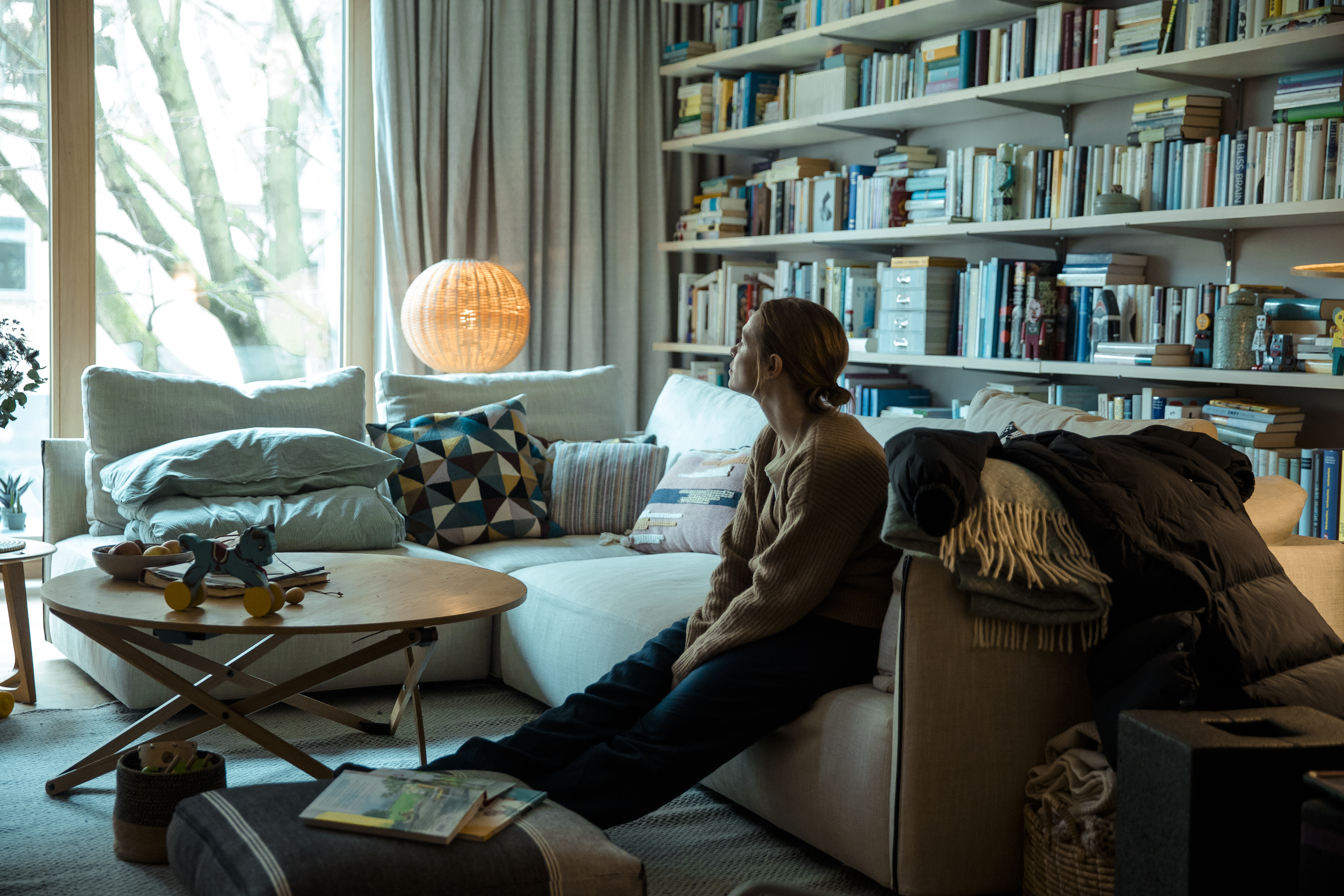 Standbild aus dem Film "Eine Milion Minuten": Vera (Karoline Herfurth) sitzt verzweifelt auf der Couch und schaut hinaus.