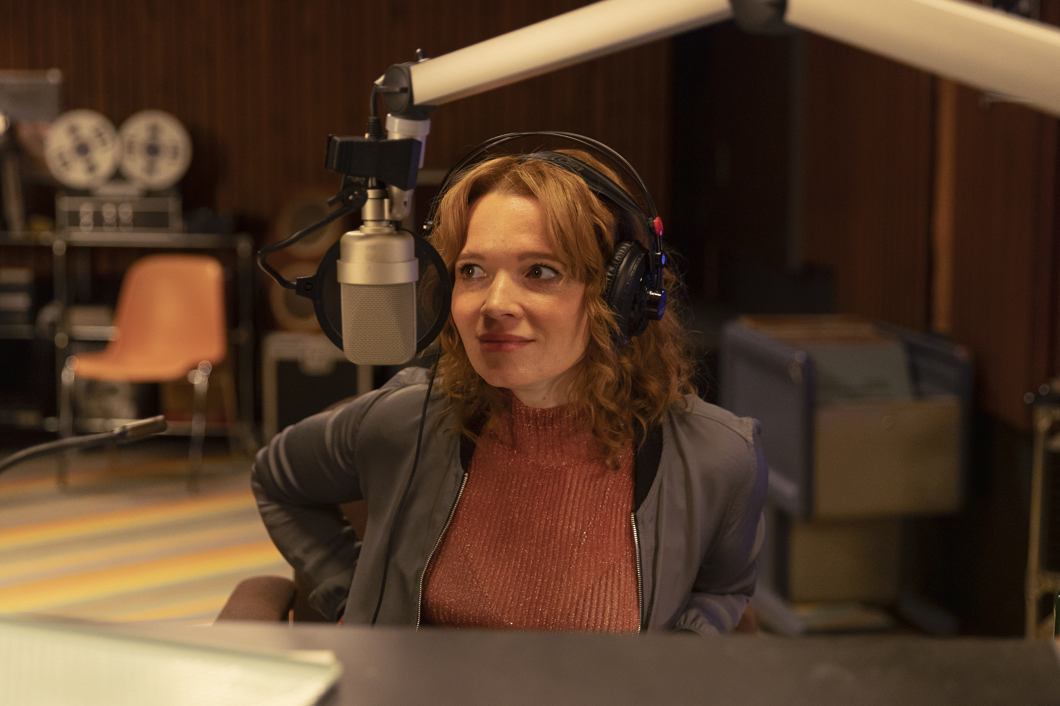 Standbild aus dem Film "Einfach mal was Schönes": Karla (Karoline Herfurth) sitzt mit Kopfhörern vor einem Mikrofon bei ihrer Arbeit im Radiosender