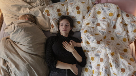 Standbild aus dem Film "Wunderschöner": Julie (Emilia Schüle) liegt weinend im Doppelbett, zwischen ihrem Neffen und ihrer Nichte.